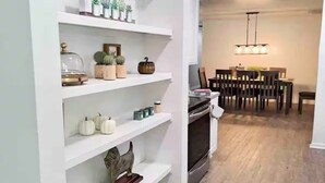Eine moderne Küche mit weißen Schränken, einem eingebauten Backofen und einem Essbereich mit Holztisch und -stühlen.