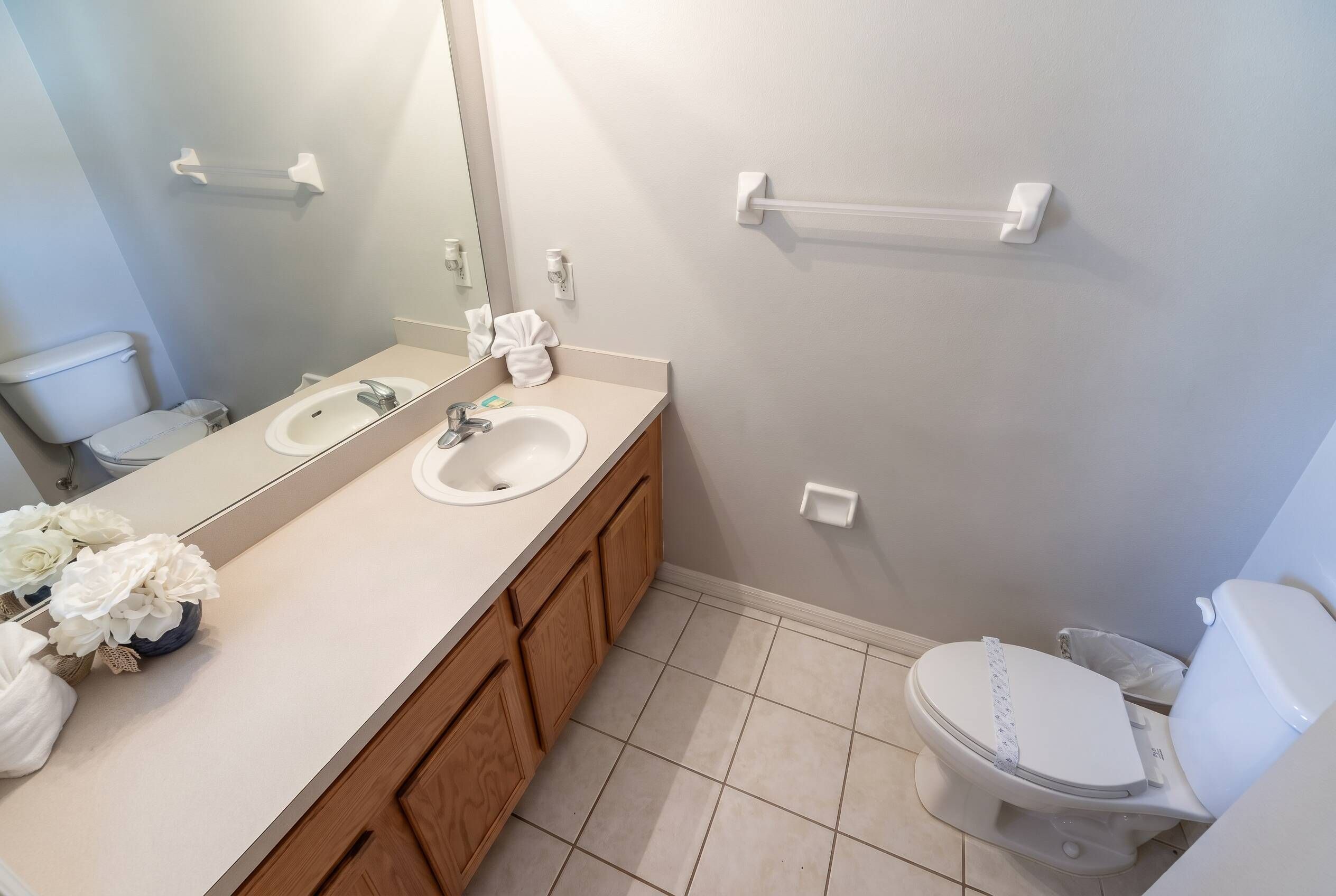 A bathroom with two sinks, a toilet, a mirror, and a towel rack.