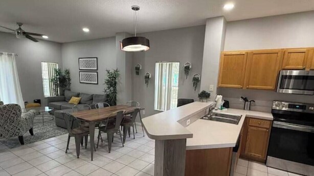 Een moderne keuken met een centraal eiland, een eetgedeelte met een houten tafel, en een woonkamer met een bank.