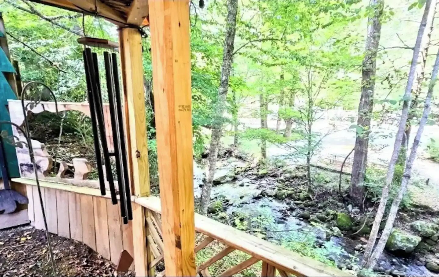 Une terrasse en bois offrant une vue sur une zone boisée et un ruisseau.