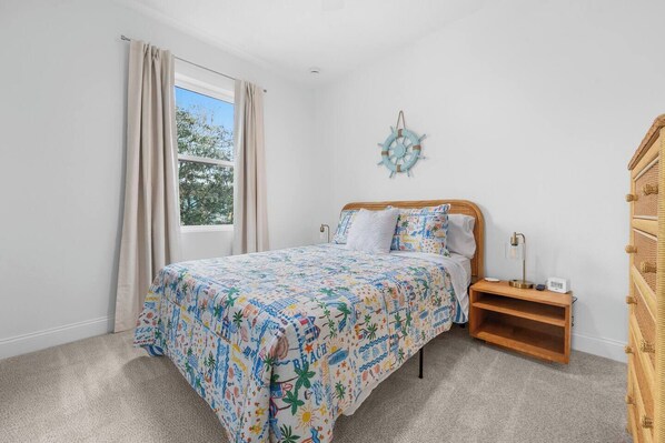 Un dormitorio con cama, mesita de noche, lámpara y un adorno en la pared.