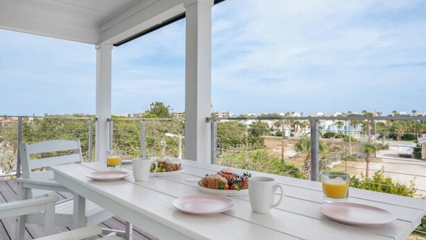 Une table blanche est placée sur un balcon, offrant une vue dégagée sur le paysage environnant.