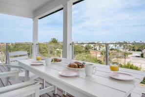 Una mesa blanca colocada en un balcón con vistas despejadas del paisaje circundante.