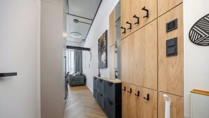 Un couloir moderne avec des meubles de rangement en bois, une console noire et un miroir.