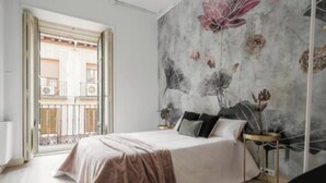 Una camera da letto con un letto, un comodino, una sedia e un grande murale floreale sulla parete.