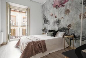A bedroom with a bed, a nightstand, a chair, and a large floral mural on the wall. - Spacious 4-Bedroom Family Apartment in La Latina with Balconies & Luxury Comfort (Madrid)