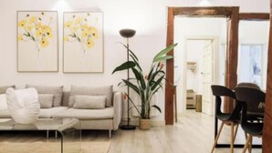 Un soggiorno moderno con un divano, un tavolino da caffè, una lampada da terra e due quadri floreali incorniciati appesi al muro.