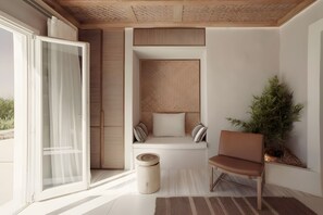 Een moderne kamer met een schuifdeur, een gewatteerde bank met kussens, een houten stoel, een klein rond tafeltje en een potplant.