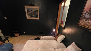 A large, multi-seater sofa bed in a dimly lit room with a dark wall and a framed picture above it. - Charming Cozy Home - Relax & Recharge (Hartington)