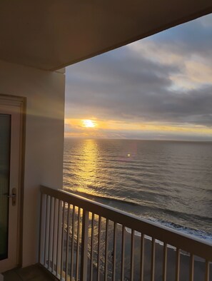 Un balcón con vista al océano al atardecer.