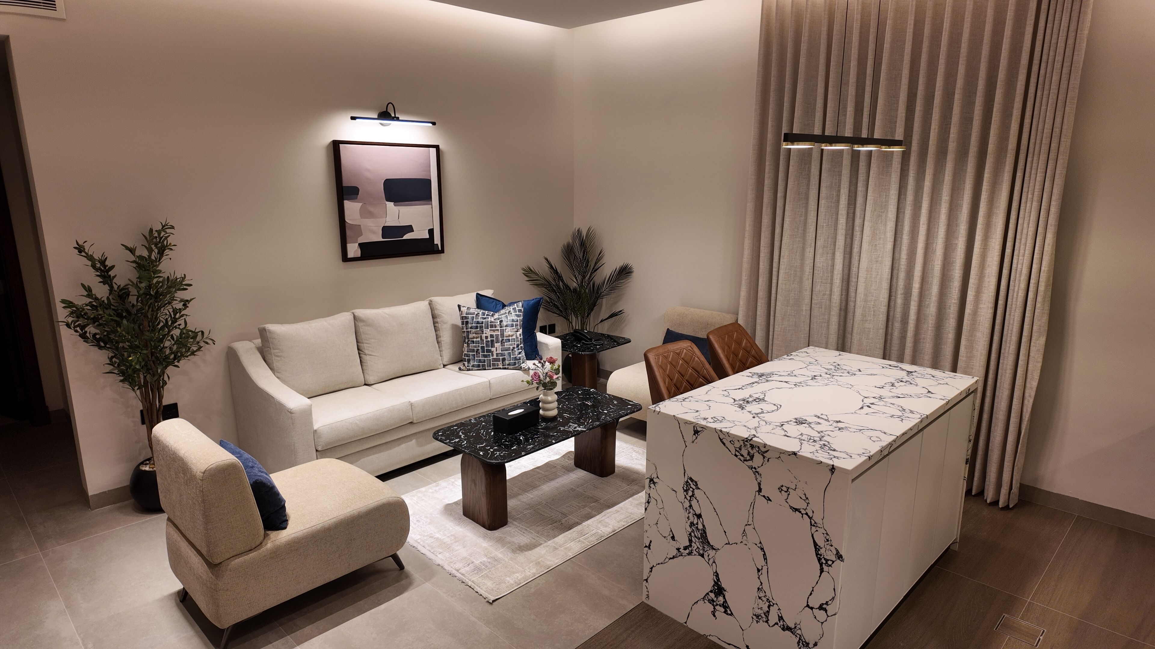 A modern living room with a sofa, armchairs, a coffee table, and a dining table.