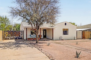 A single-story house with a patio, a tree, and a fenced yard.
