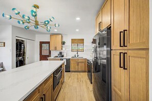 A modern kitchen with wooden cabinets, a stainless steel refrigerator, and a marble countertop. - Charming 3-bedroom house with AC in sunny Phoenix (Phoenix)