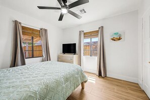 A bedroom with a bed, a television, a ceiling fan, and windows with curtains. - Charming 3-bedroom house with AC in sunny Phoenix (Phoenix)