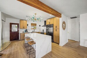 A modern kitchen with a large island, wooden cabinets, and a stainless steel refrigerator. - Charming 3-bedroom house with AC in sunny Phoenix (Phoenix)