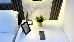A small, white desk with a smartphone, a framed picture, and a potted plant. - Urban Oasis Partition Room in Al Barsha1 (Dubai)