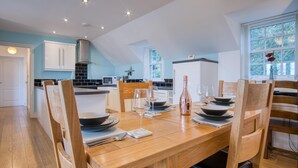 A modern kitchen with a dining area set for six. - Bayview 2 - 2 Bedroom Cottage - Penally (Tenby)