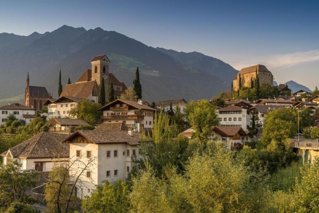 Un pueblo montañoso con arquitectura tradicional, que incluye una iglesia y un edificio similar a un castillo.