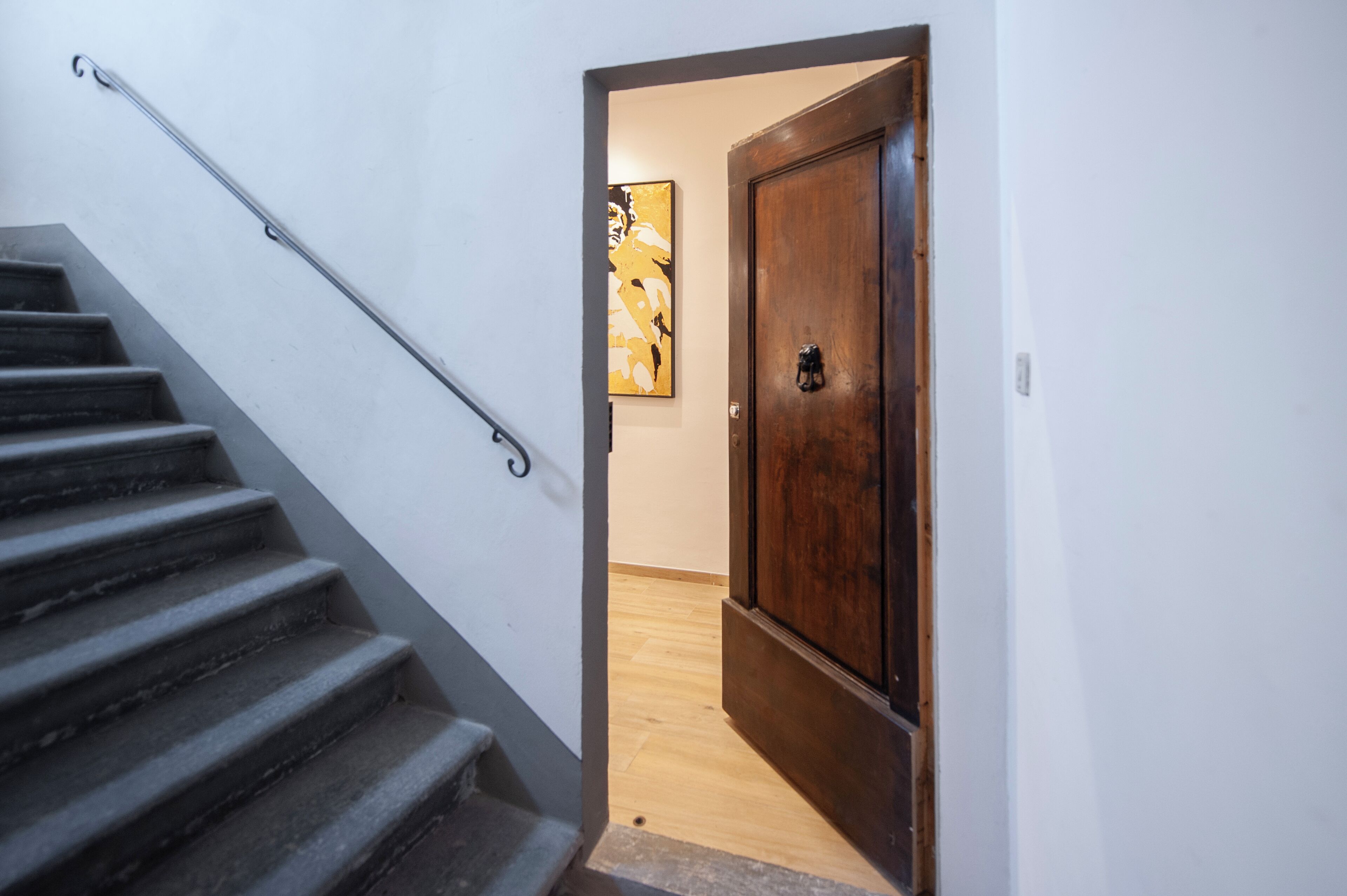 Eine Treppe mit einem Metallgeländer, das zu einer Holztür mit einer verzierten Klinke führt.