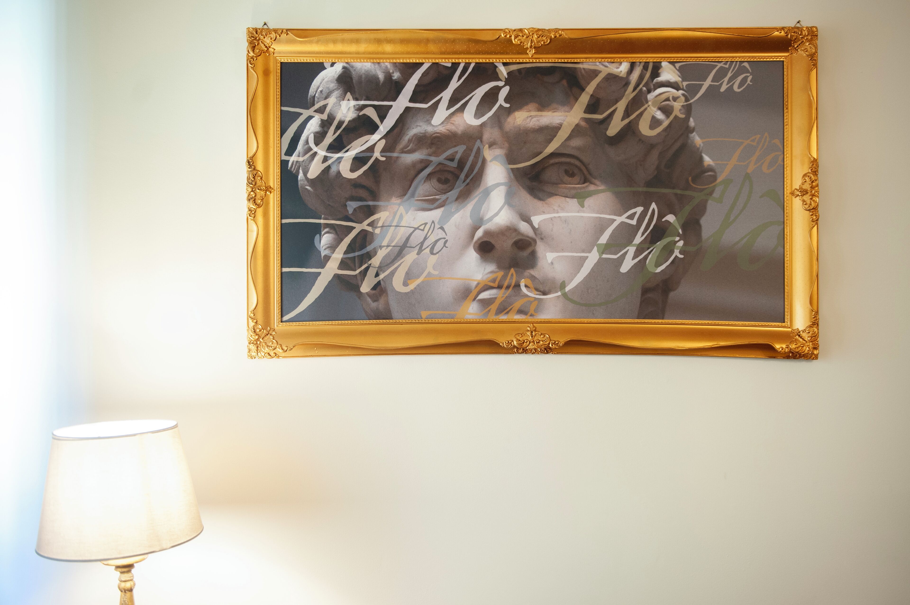 A framed artwork with a gold ornate frame on a wall.
