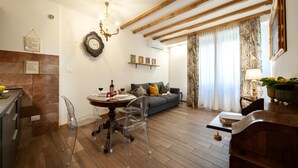 A modern living room with a dining table, clear chairs, a sofa, and a chandelier. - Casa Sorelle Flo - Flo Apartments (Florence)