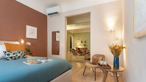 Una habitación de hotel moderna con una cama grande, una mesita con un florero y una silla.