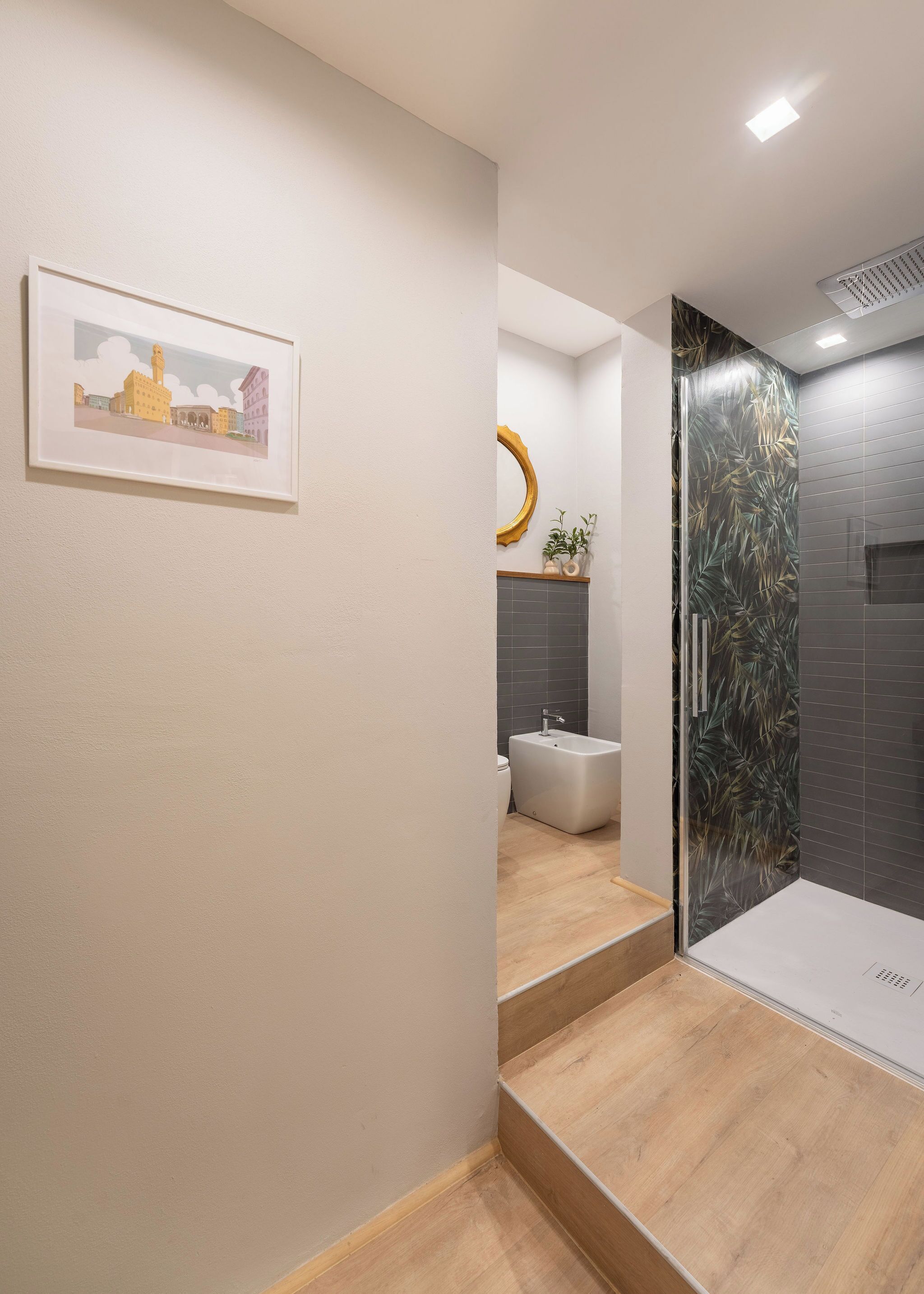 Ein modernes Badezimmer mit Dusche, Toilette und Waschbecken. An der Wand hängt ein gerahmtes Bild und über dem Waschbecken befindet sich ein Spiegel.