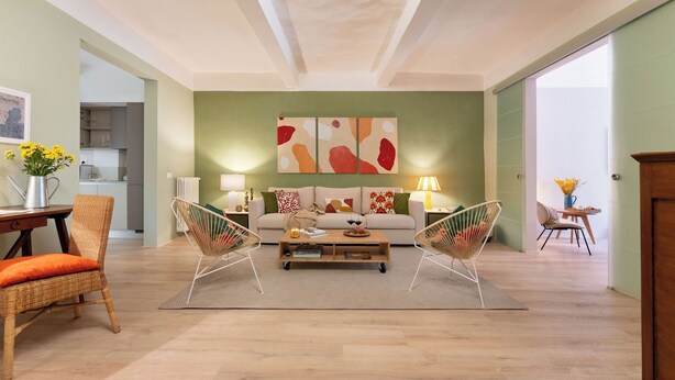 Un salón amplio con un sofá, dos sillones, una mesa de centro y un cuadro en la pared.