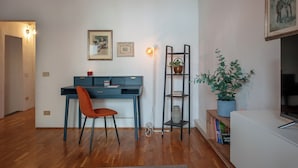 A modern living room with a blue desk, a red chair, a potted plant, and a bookshelf. - Ricasoli 37 - Flo Apartments (Florence)