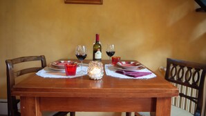 A wooden dining table with two chairs, a candle, and two wine glasses on a placemat. - Cate Apartment - Flo Apartments (Florence)