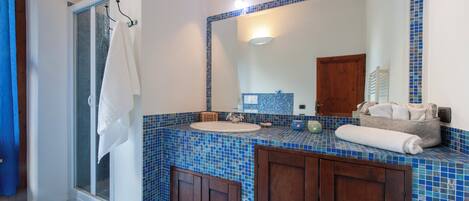 Une salle de bain avec un lavabo aux carreaux bleus, un miroir et des meubles en bois.