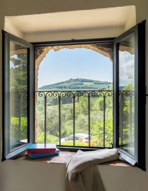 A room with a large window overlooking a green landscape and a hill. - La Casa di Madina - Flo Apartments (Montespertoli)
