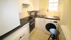 A compact kitchen with a microwave, oven, sink, and washing machine. - Fabulous Apartment Near Central London (London)