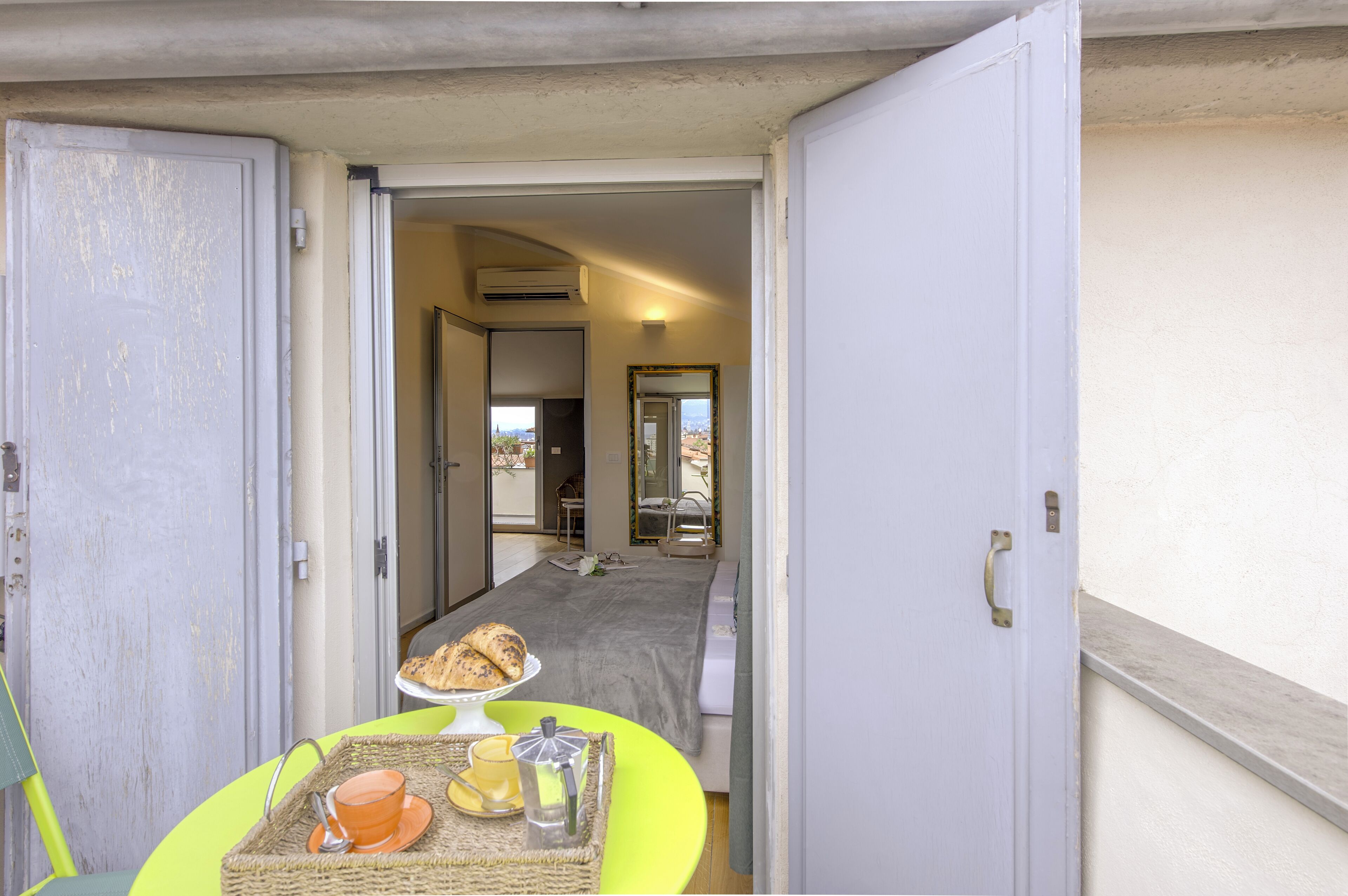 A room with a bed, a table with breakfast items, and a view of the outside.
