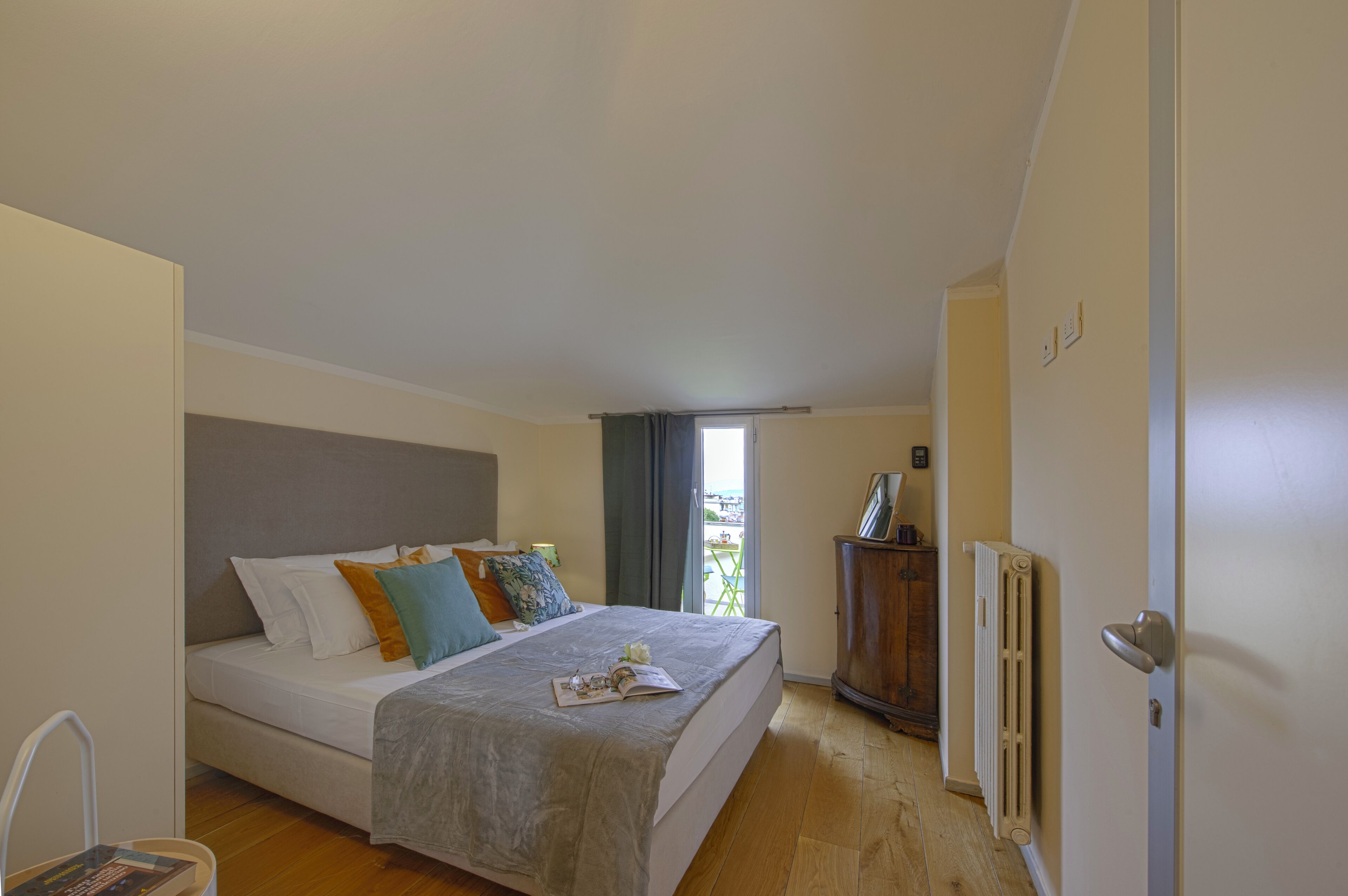 Een slaapkamer met een bed, een radiator, een houten kast en een raam met gordijnen.