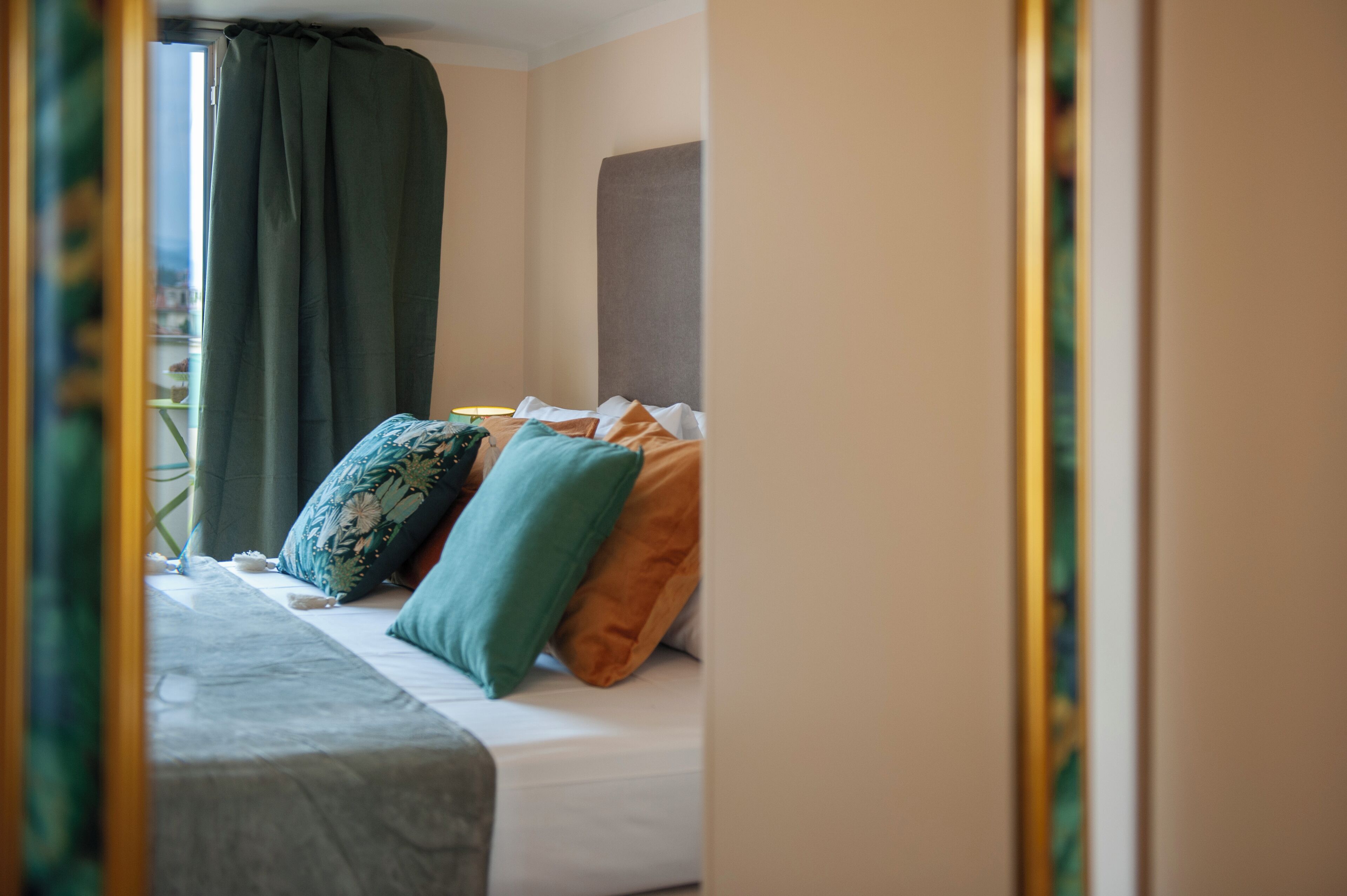 Une chambre à coucher avec un lit, des oreillers, une table de chevet et une fenêtre avec des rideaux.
