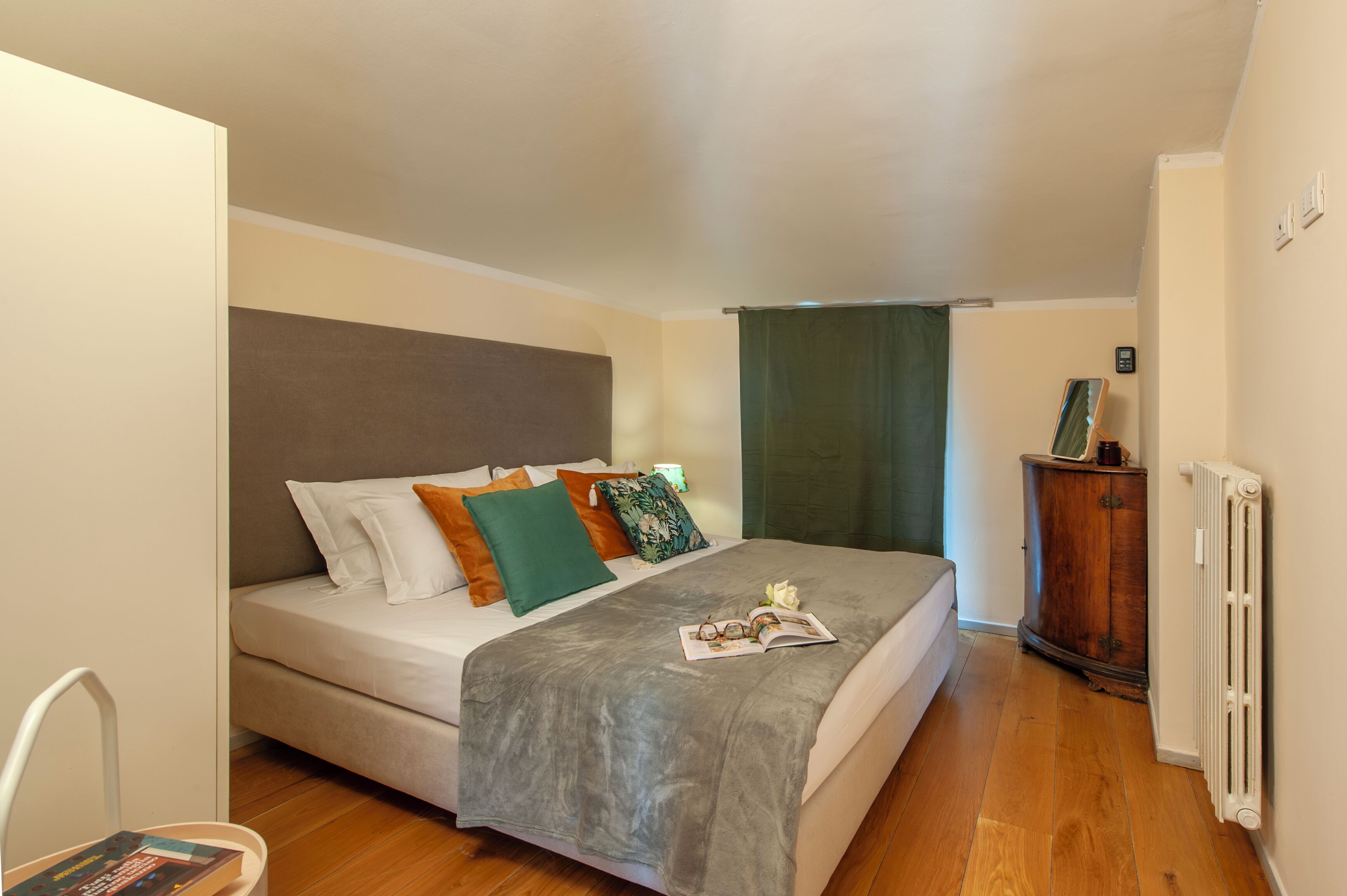 A bedroom with a bed, a wooden cabinet, and a radiator.