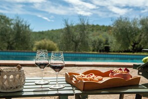 A table with two wine glasses and a basket of bread by a poolside. - Poggio ai Pianacci - Flo Apartments (Greve in Chianti)