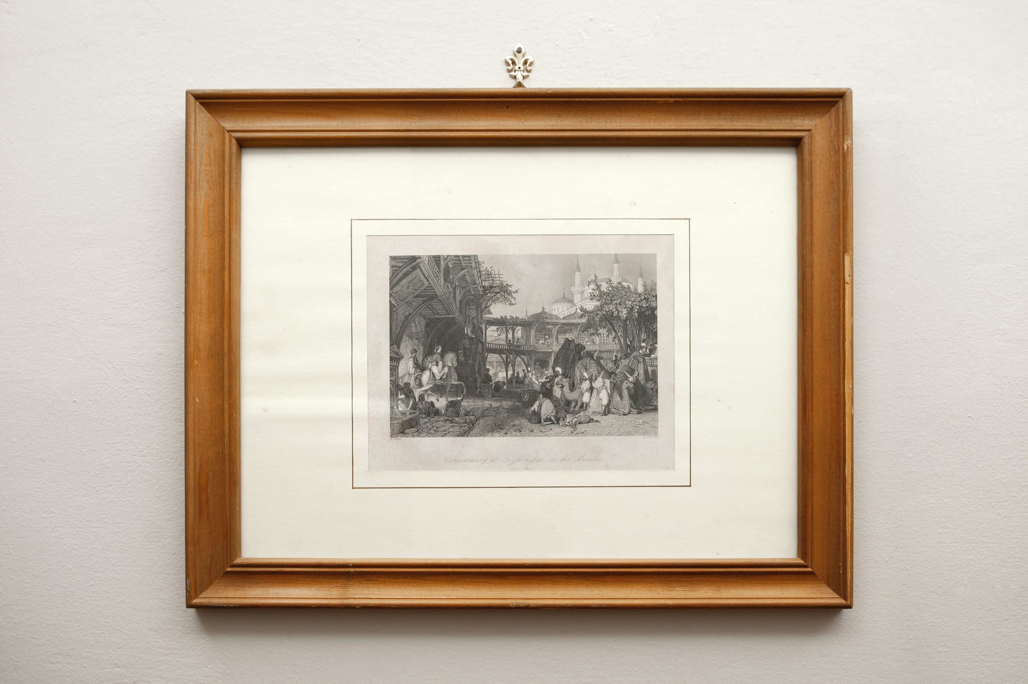 A framed black and white historical illustration of a bustling market scene with buildings and people.