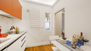 Eine moderne Küche mit weißen Schränken, einer Marmor-Spritzschutzwand und einem Essbereich mit Tisch für zwei Personen.