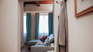 Ein gemütliches Wohnzimmer mit grauem Sofa, blaugrünen Vorhängen und einer Holzbalkendecke.