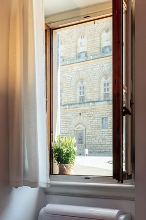 Ein Fenster mit Blick auf ein Gebäude mit Bogenfenstern und einer Steinfassade.