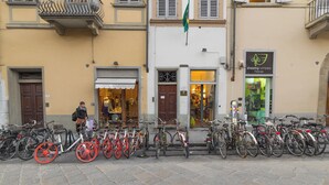 A row of bicycles parked in front of a building with a flag, a person, and a sign for a shipping company. - Pitti - Flo Apartments, Charme su Piazza Pitti (Florence)