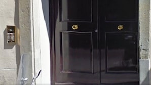 A black double door with a decorative metal crest above it. - Boboli - Flo Apartments (Florence)