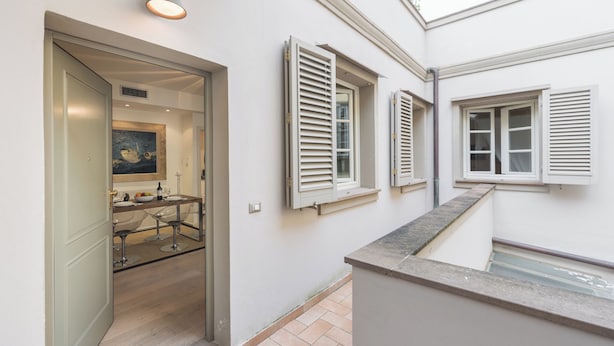 A modern interior with a kitchen area, a dining space with bar stools, and a staircase leading to an upper level. - Boboli - Flo Apartments (Florence)