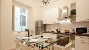Une cuisine moderne avec des meubles blancs, une table à manger en verre et des chaises blanches.