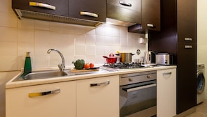 Une cuisine moderne équipée d’un évier en acier inoxydable, d’une cuisinière à gaz, d’un four à micro-ondes et d’un four encastré.