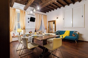 A dining area with a wooden table, chairs, and a blue sofa. - Signoria - Flo Apartments (Florence)