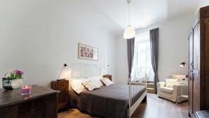 A bedroom with a bed, bedside table, lamp, and a chair. - Campuccio - Flo Apartments (Florence)