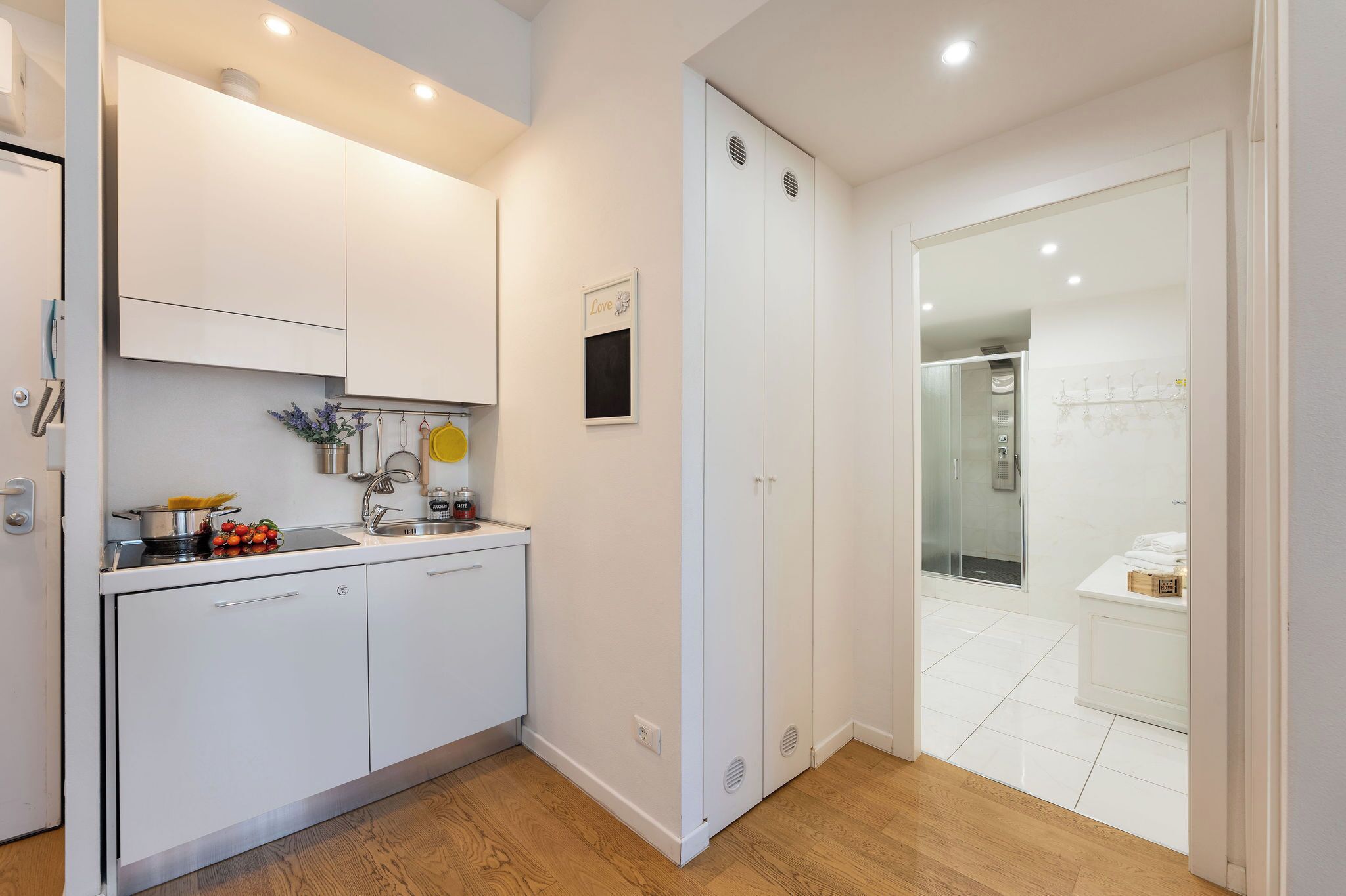 Una cocina moderna con armarios blancos, un fregadero y una encimera con utensilios de cocina.